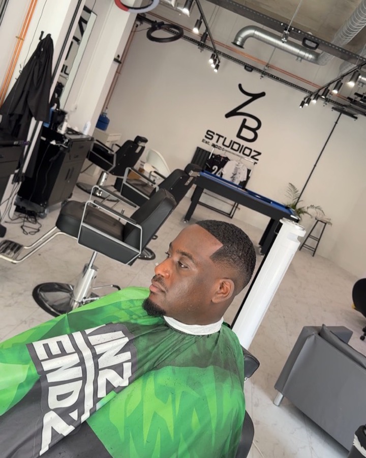 Fresh low fade finished in the chair, ZB Studioz logo on the wall behind