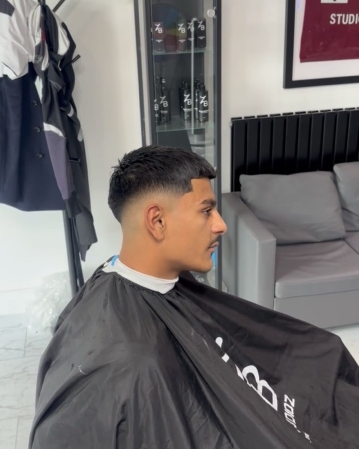 Skin fade with a sharp line-up, seen in profile